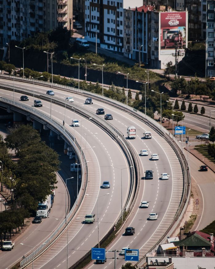 Aerial view of a curved highway in Giresun, Türkiye, showcasing urban architecture and vehicles.